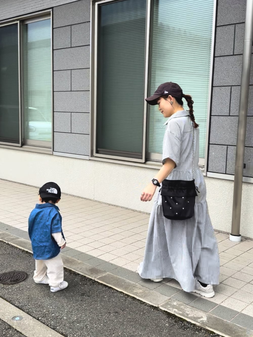 ブラック系のワンピース、ホワイト系のスニーカー、ブラック系のショルダーバッグを着用したレディースの夏コーディネートの5枚目の写真