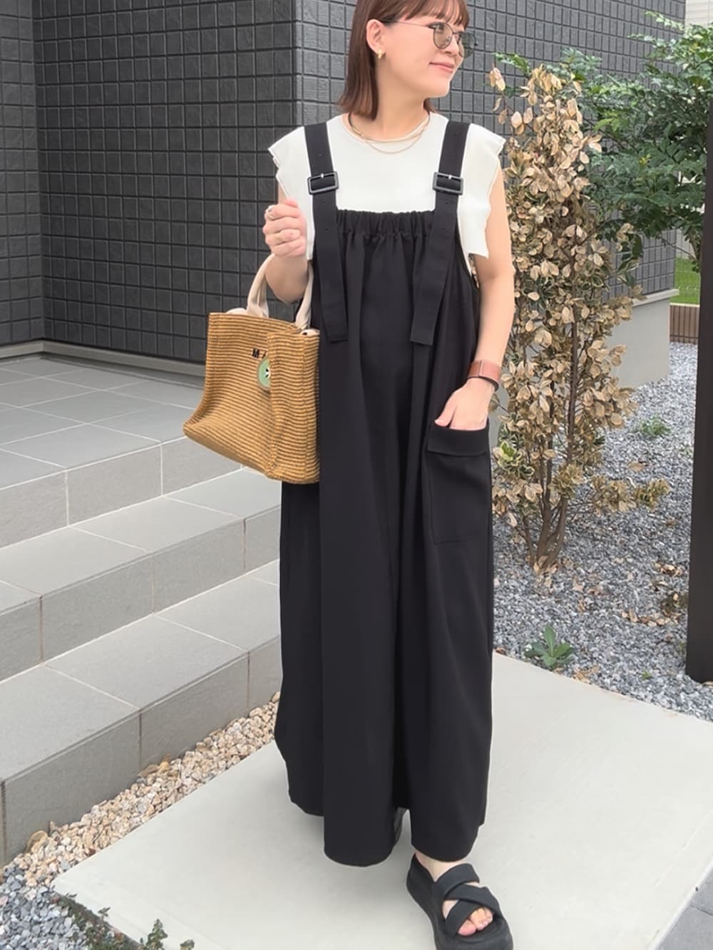 ブラック系のジャンパースカート、ホワイト系のニット/セーター、ベージュ系のショルダーバッグを着用したレディースの秋コーディネートの2枚目の写真