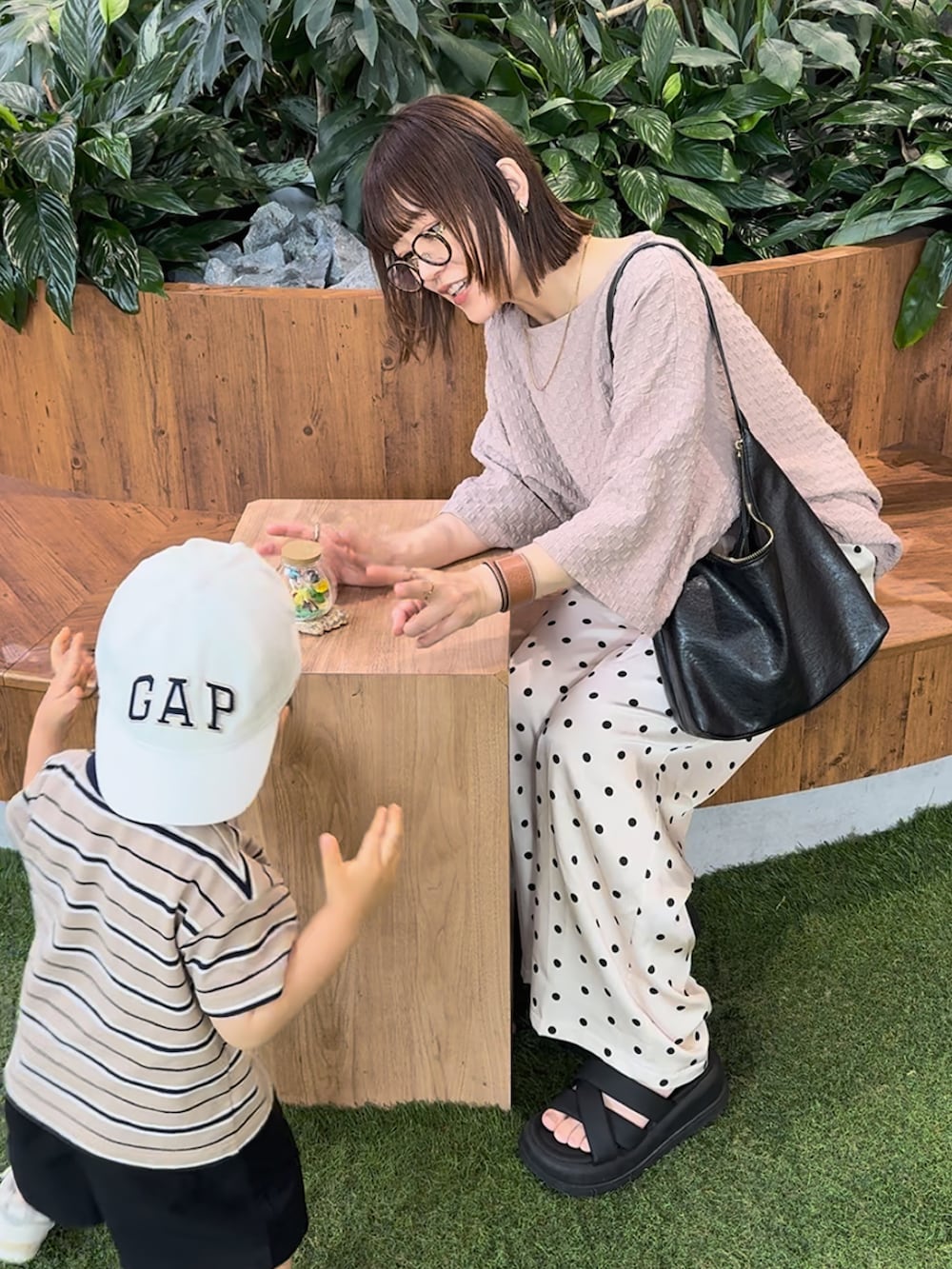 ベージュ系のTシャツ/カットソー、ホワイト系のパンツ、ブラック系のバッグを着用したレディースの夏コーディネートの2枚目の写真