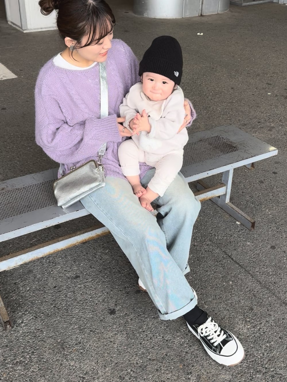 パープル系のニット/セーター、ブルー系のデニムパンツ、ブラック系のスニーカーを着用したレディースの春コーディネートの2枚目の写真