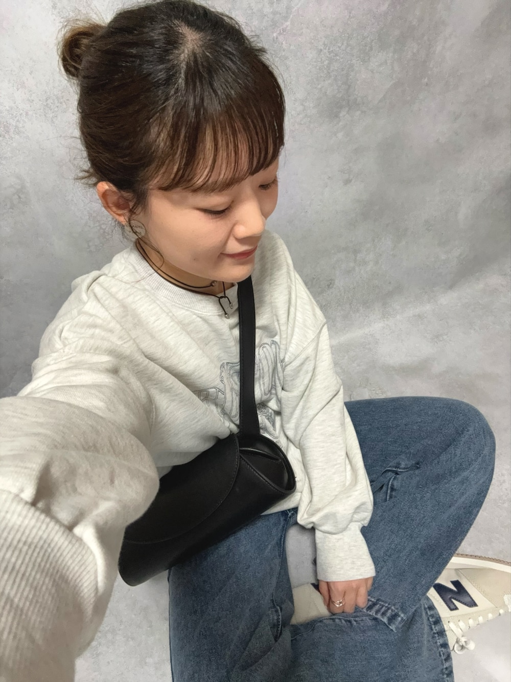 グレー系のスウェット、ブラック系のショルダーバッグ、ブラック系のスカートを着用したレディースの秋コーディネートの3枚目の写真