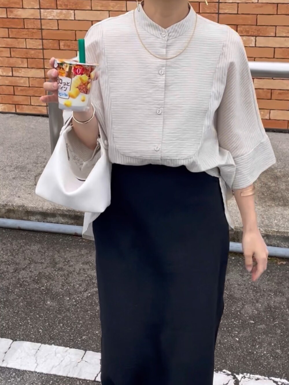 グレー系のシャツ/ブラウス、ブラック系のスカート、ホワイト系のハンドバッグを着用したレディースの春コーディネートの3枚目の写真