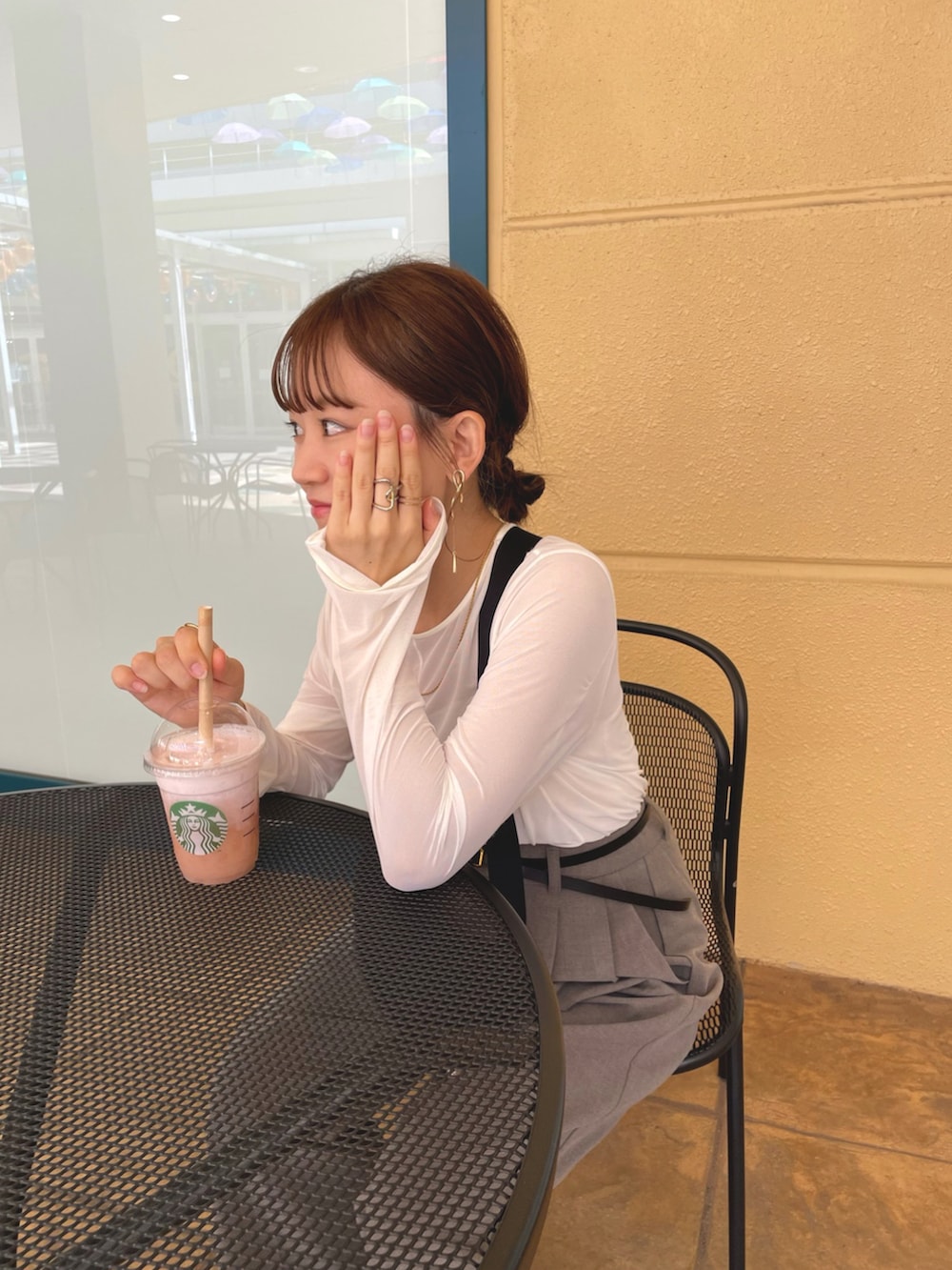 ホワイト系のトップス、ブラウン系のパンツ、ブラック系のショルダーバッグを着用したレディースの夏コーディネートの3枚目の写真
