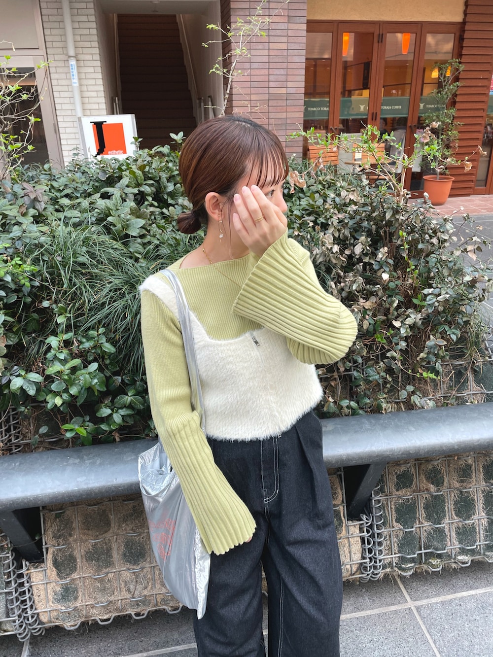 グリーン系のニット/セーター、ホワイト系のベスト、ブラック系のデニムパンツを着用したレディースの春コーディネートの2枚目の写真