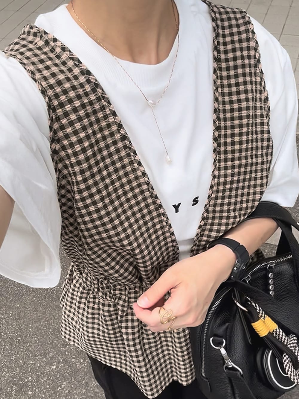 ブラック系のスウェットパンツ、ブラウン系のベスト、ホワイト系のTシャツ/カットソーを着用したレディースの夏コーディネートの3枚目の写真