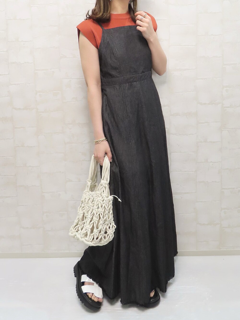 ブラック系のワンピース、オレンジ系のニット/セーター、ホワイト系のハットを着用したレディースの春コーディネートの2枚目の写真