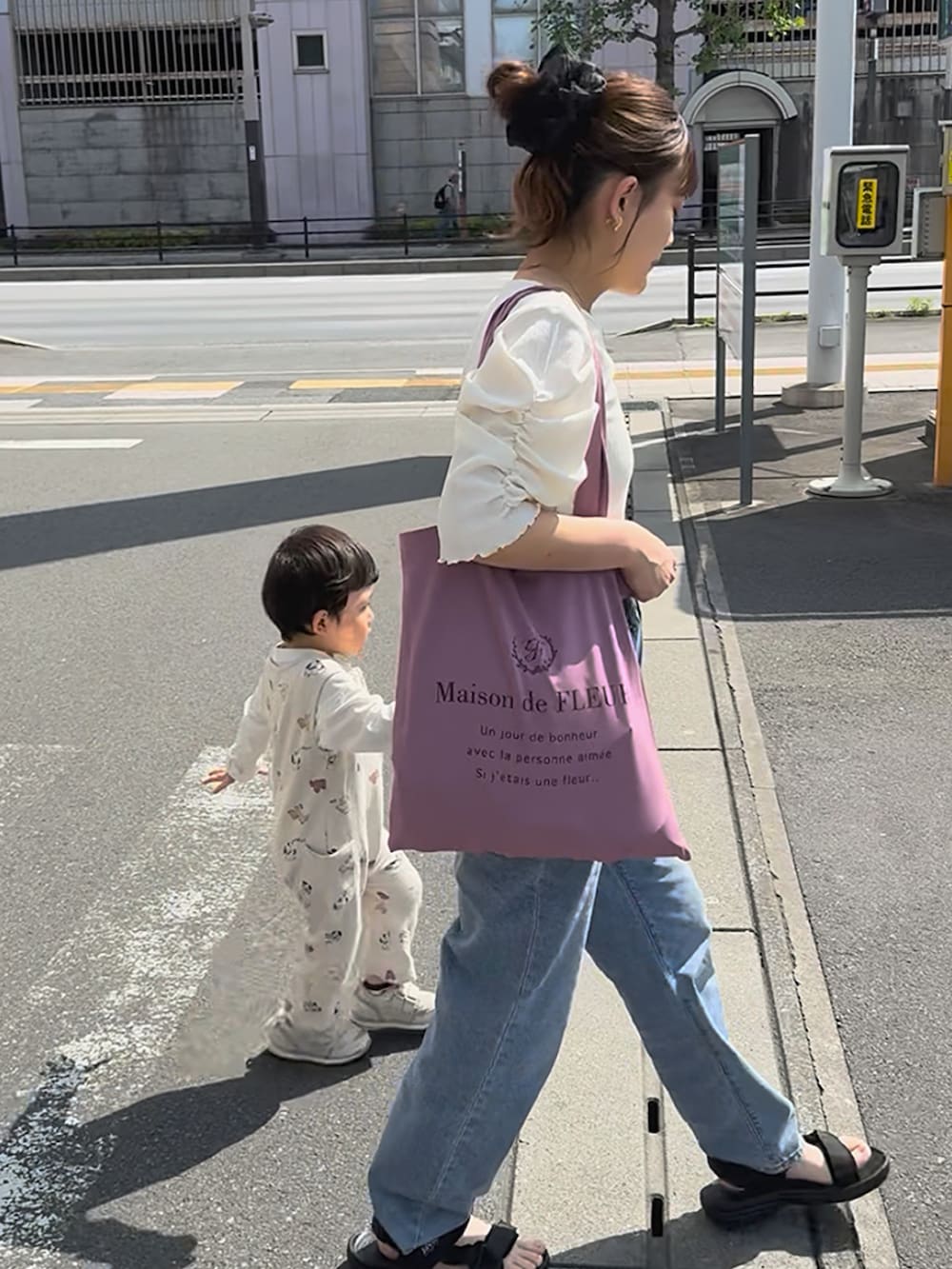ブラック系のサンダル、ホワイト系のトップス、ブルー系のデニムパンツを着用したレディースの夏コーディネートの3枚目の写真