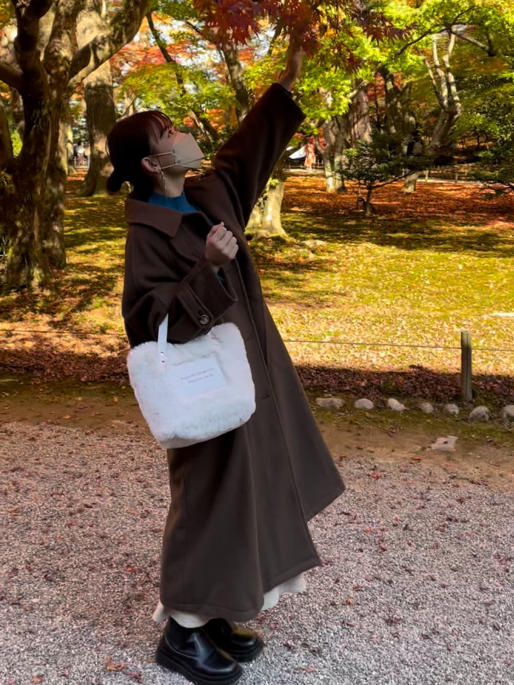 ブラウン系のステンカラーコート、ブルー系のニット/セーター、ベージュ系のスカートを着用したレディースの秋コーディネートの5枚目の写真