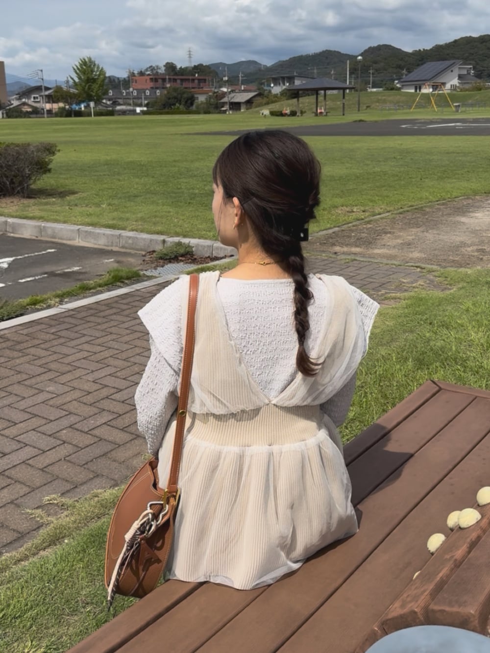 ホワイト系のTシャツ/カットソー、ブラウン系のショルダーバッグ、ベージュ系のベストを着用したレディースの秋コーディネートの3枚目の写真