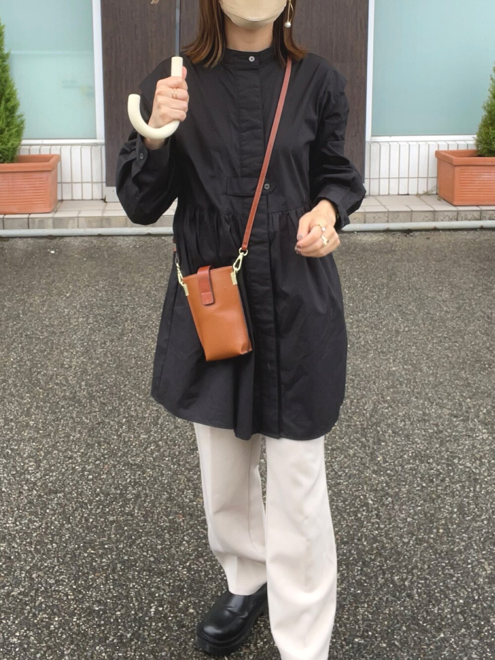 ブラック系のチュニック、ブラウン系のショルダーバッグ、ホワイト系のスラックスを着用したレディースの秋コーディネートの2枚目の写真