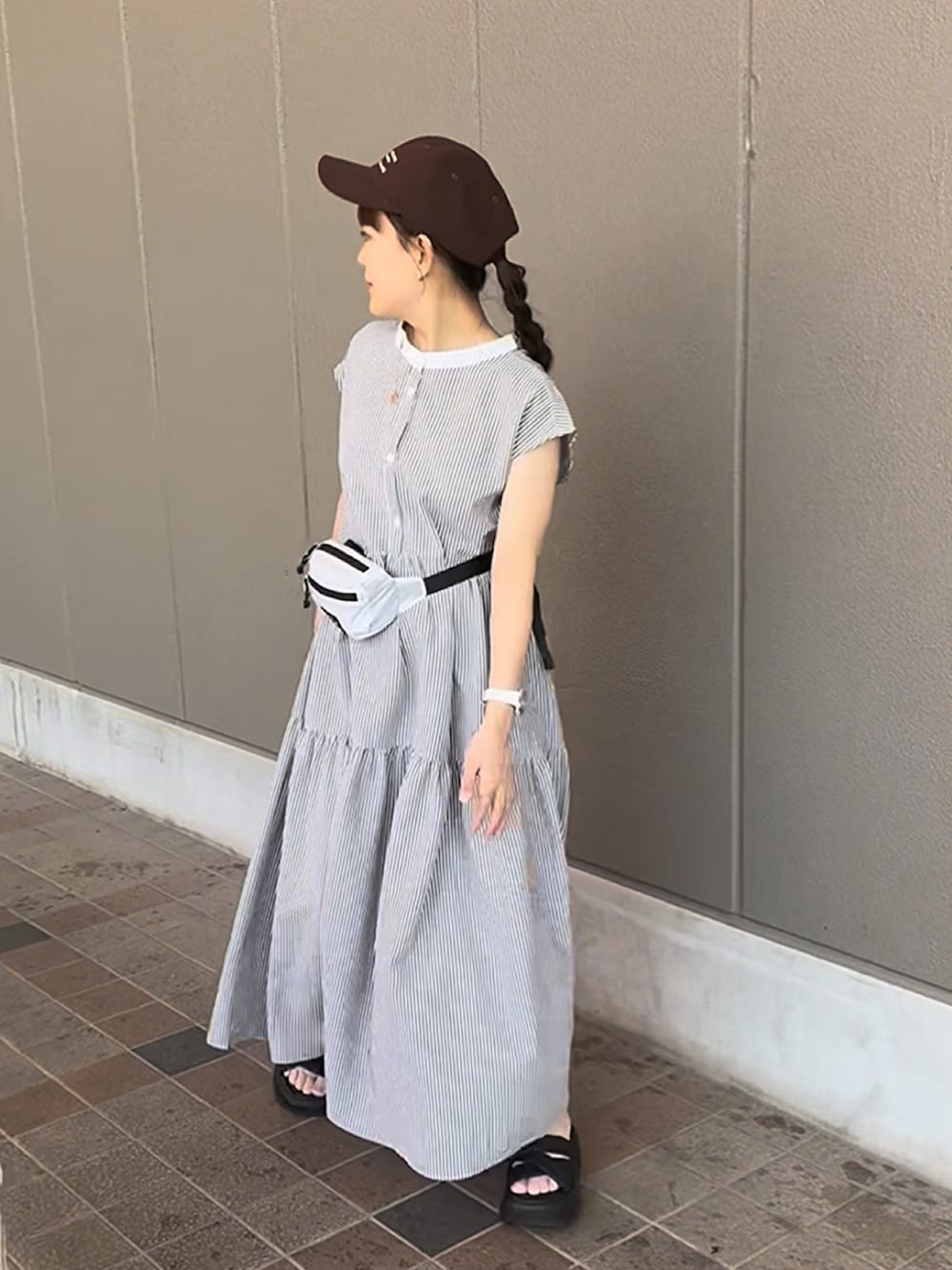 ブラック系のワンピース、ブラック系のサンダル、ブラウン系のキャップを着用したレディースの夏コーディネートの3枚目の写真