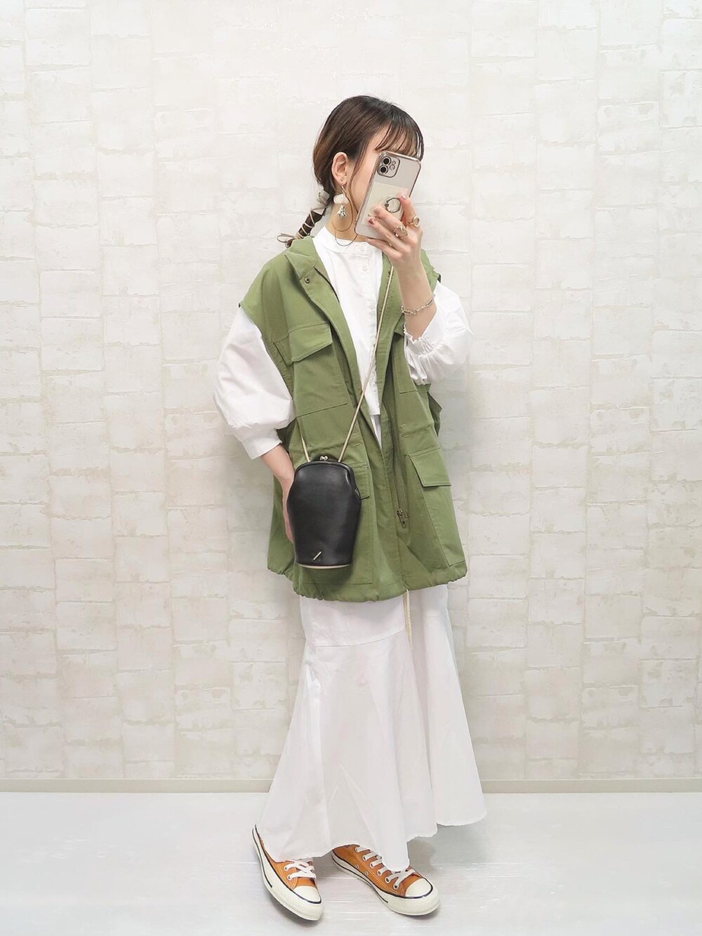 ホワイト系のワンピース、グリーン系のベスト、ブラック系のショルダーバッグを着用したレディースの春コーディネートの2枚目の写真