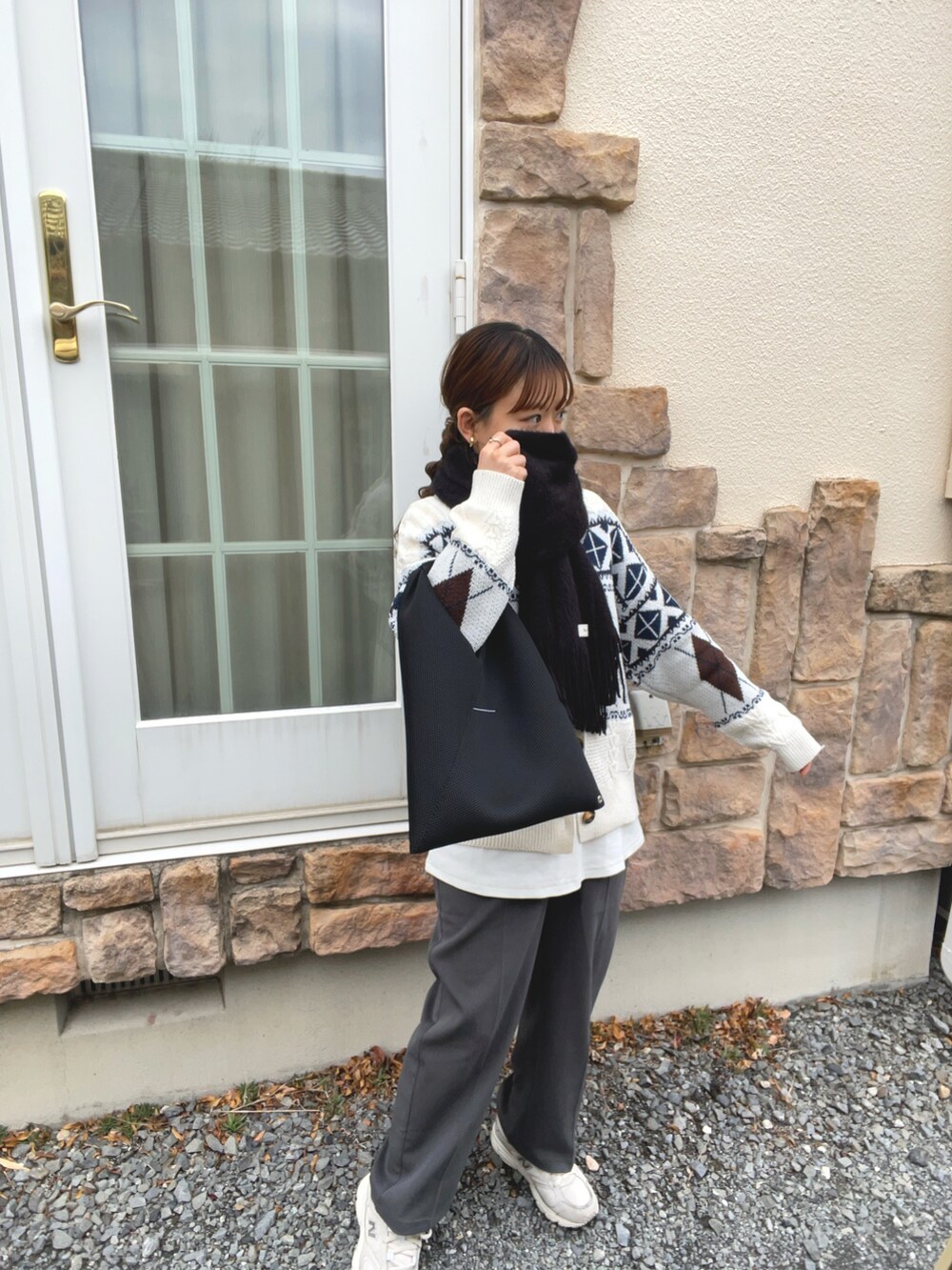 ベージュ系のニット/セーター、グレー系のその他パンツ、ブラック系のマフラーを着用したレディースの冬コーディネートの2枚目の写真