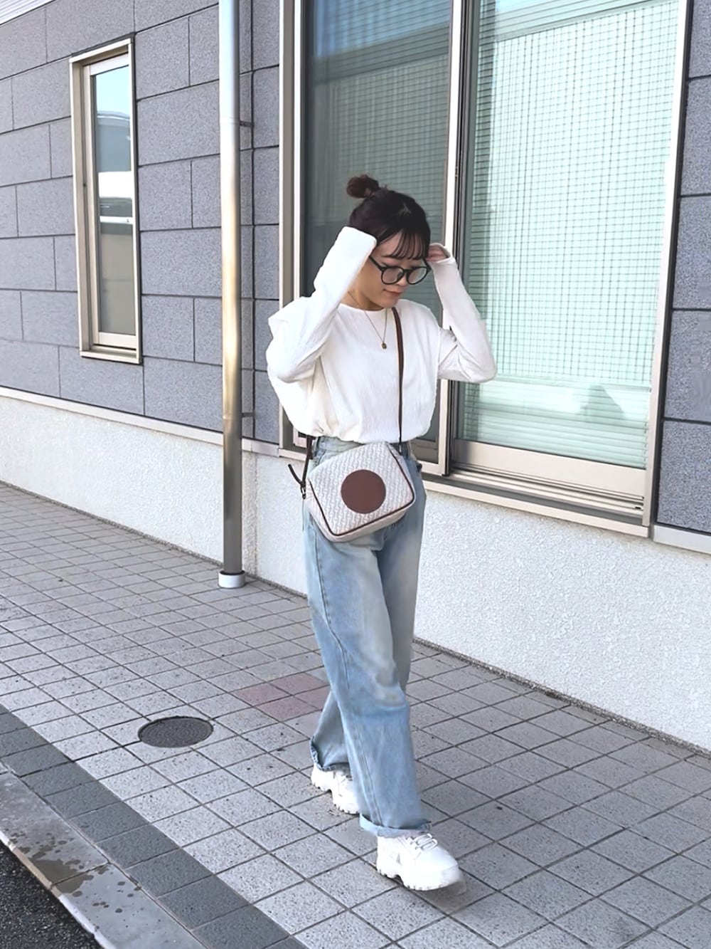 ホワイト系のTシャツ/カットソー、ブルー系のデニムパンツ、ホワイト系のショルダーバッグを着用したレディースの冬コーディネートの2枚目の写真