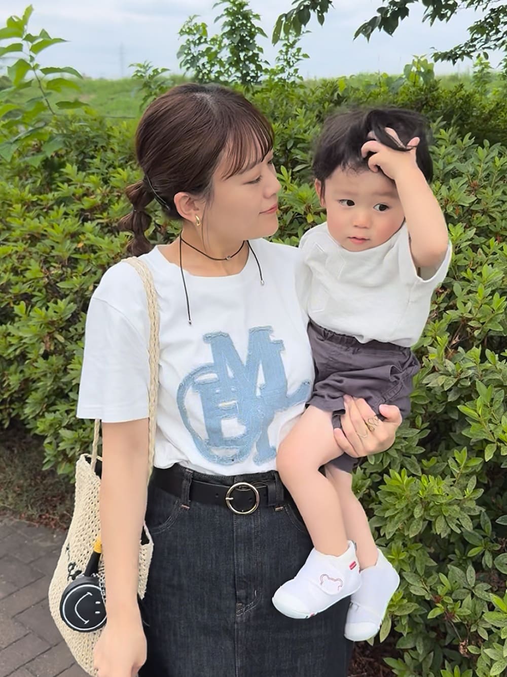 ホワイト系のTシャツ/カットソー、ブラック系のデニムスカート、ベージュ系のかごバッグを着用したレディースの夏コーディネートの3枚目の写真