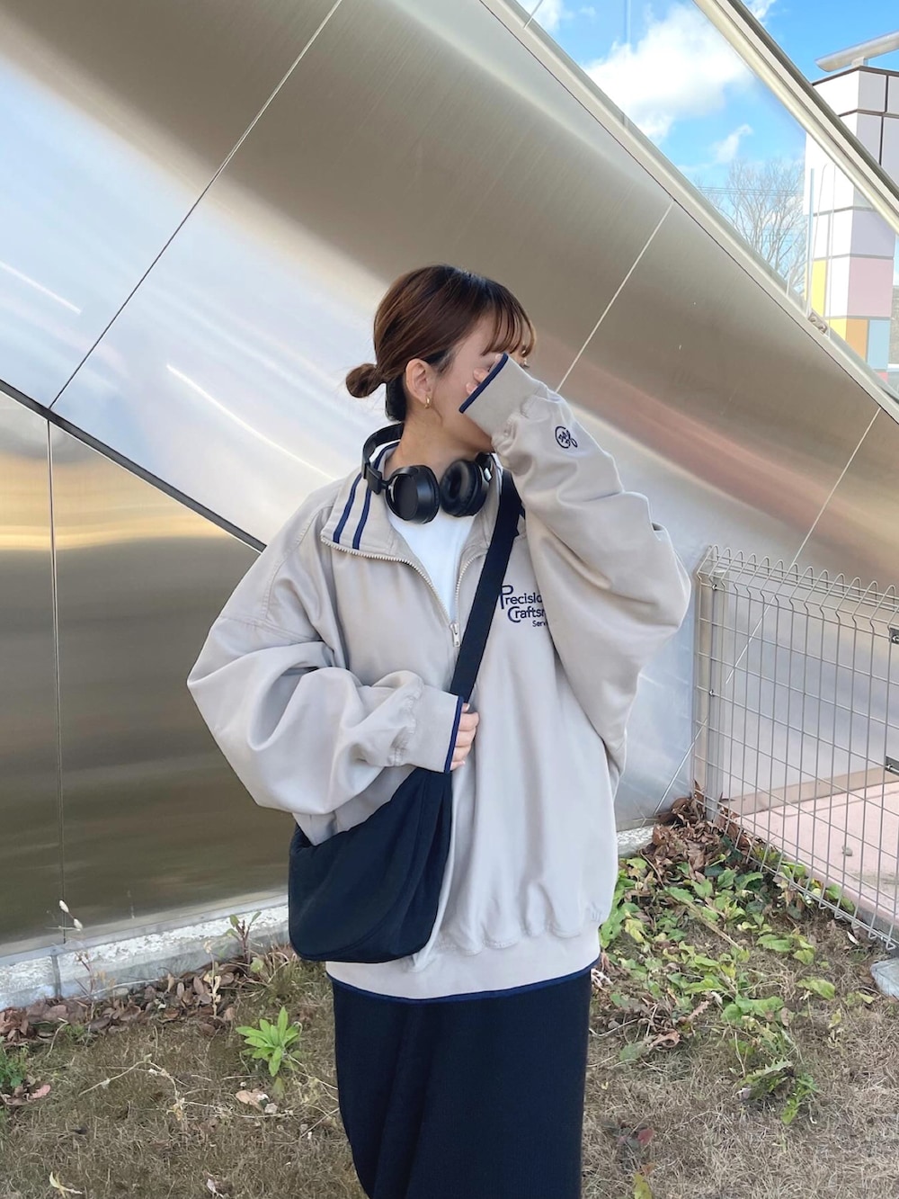 ベージュ系のスウェット、ブラック系のショルダーバッグ、ホワイト系のスニーカーを着用したレディースの冬コーディネートの3枚目の写真