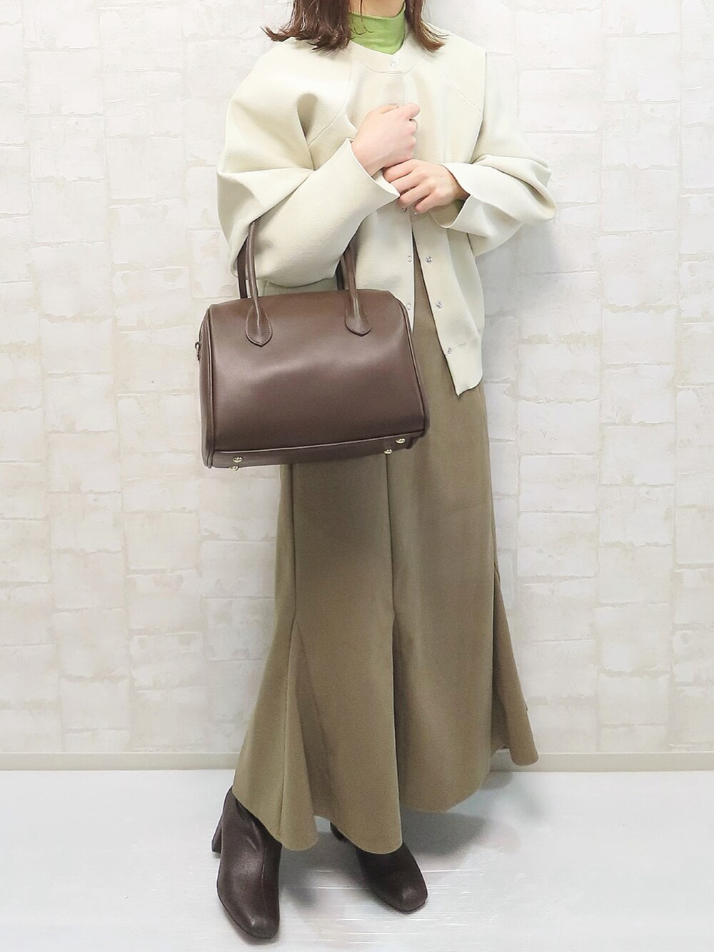 ベージュ系のニット/セーター、グリーン系のニット/セーター、ブラック系のデニムパンツを着用したレディースの冬コーディネートの4枚目の写真