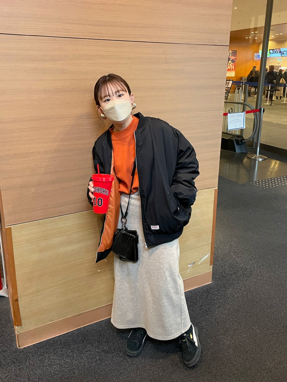 ブラック系のMA-1、オレンジ系のニット/セーター、ベージュ系のスカートを着用したレディースの冬コーディネートの3枚目の写真