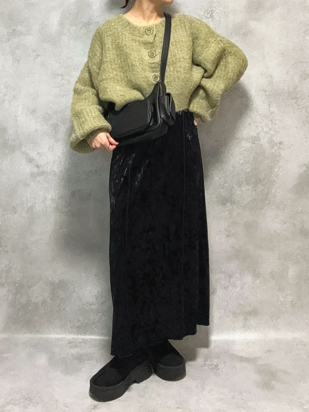 グリーン系のカーディガン/ボレロ、ブラック系のワンピース、ブラック系のショルダーバッグを着用したレディースの秋コーディネートの2枚目の写真