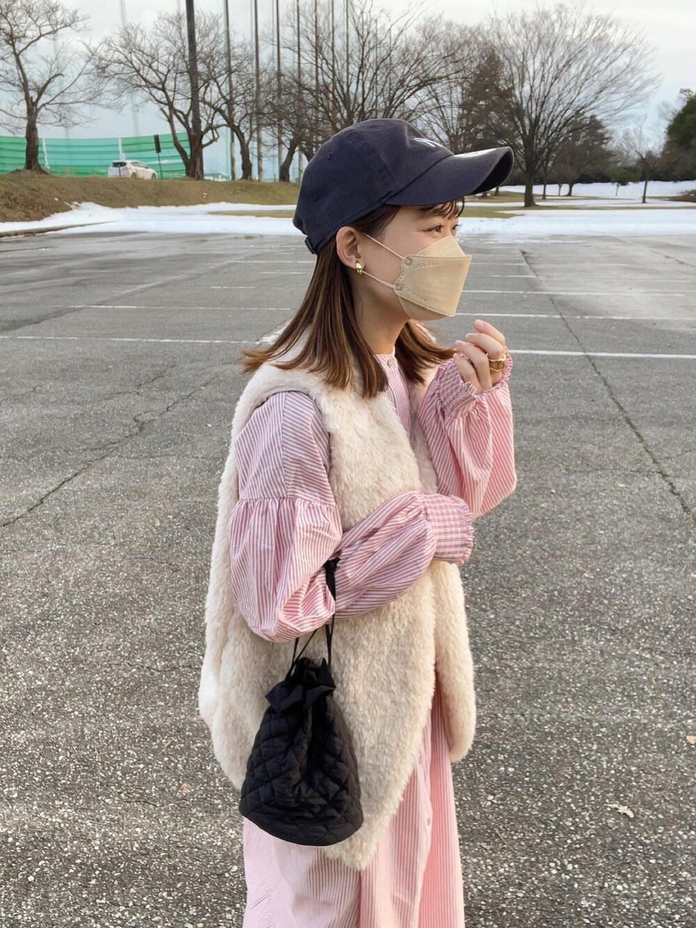 レッド系のワンピース、グレー系のベスト、ブラック系のショルダーバッグを着用したレディースの冬コーディネートの2枚目の写真