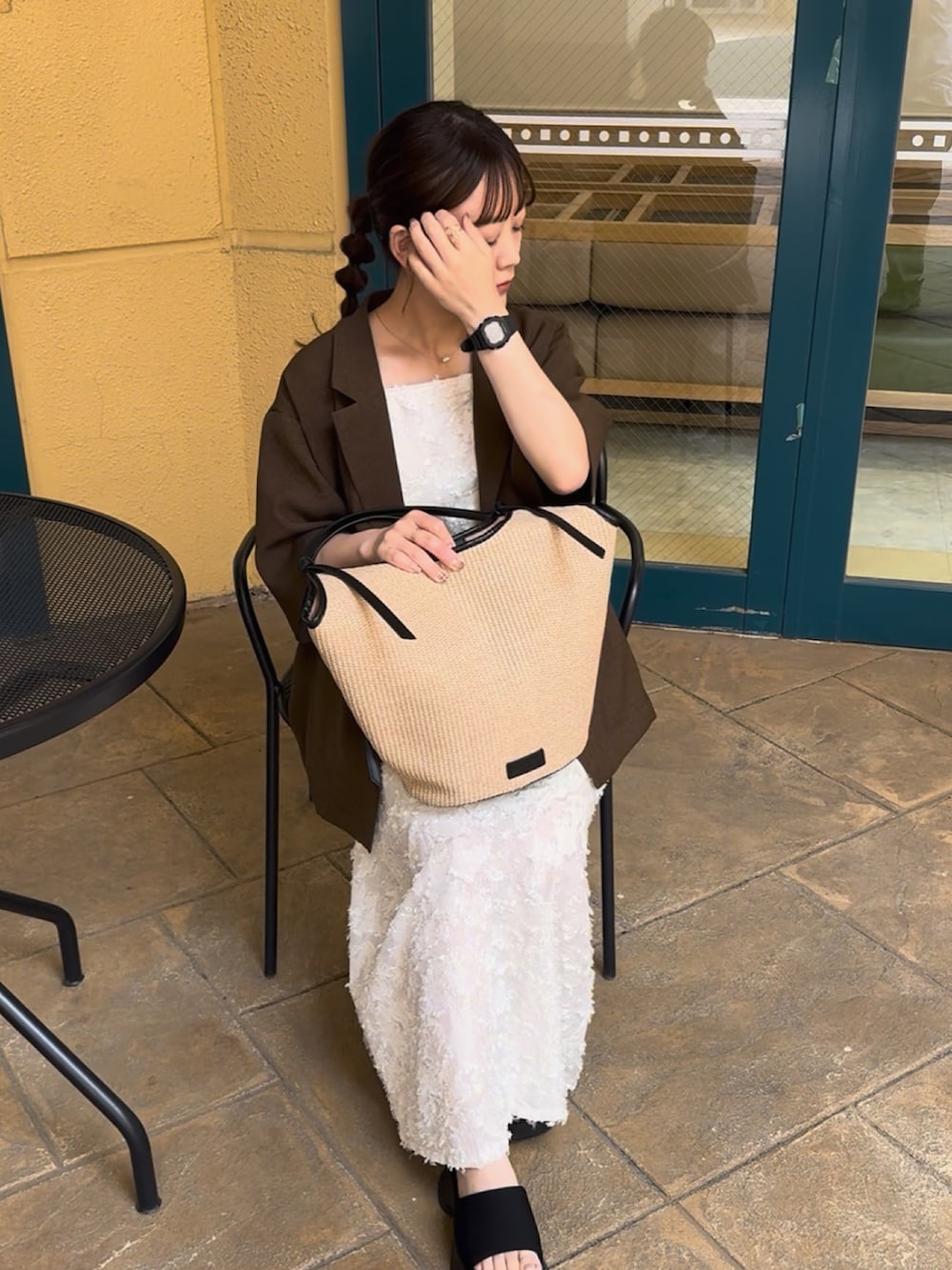 ブラウン系のテーラードジャケット、ブラック系のトートバッグ、ホワイト系のワンピース/ドレスを着用したレディースの夏コーディネートの3枚目の写真