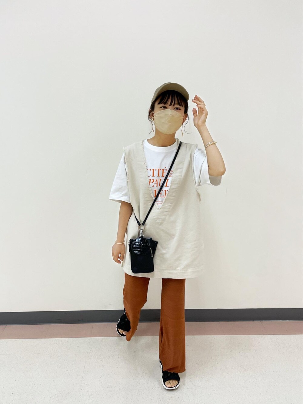ブラウン系のその他パンツ、ホワイト系のベスト、オレンジ系のTシャツ/カットソーを着用したレディースの夏コーディネートの5枚目の写真