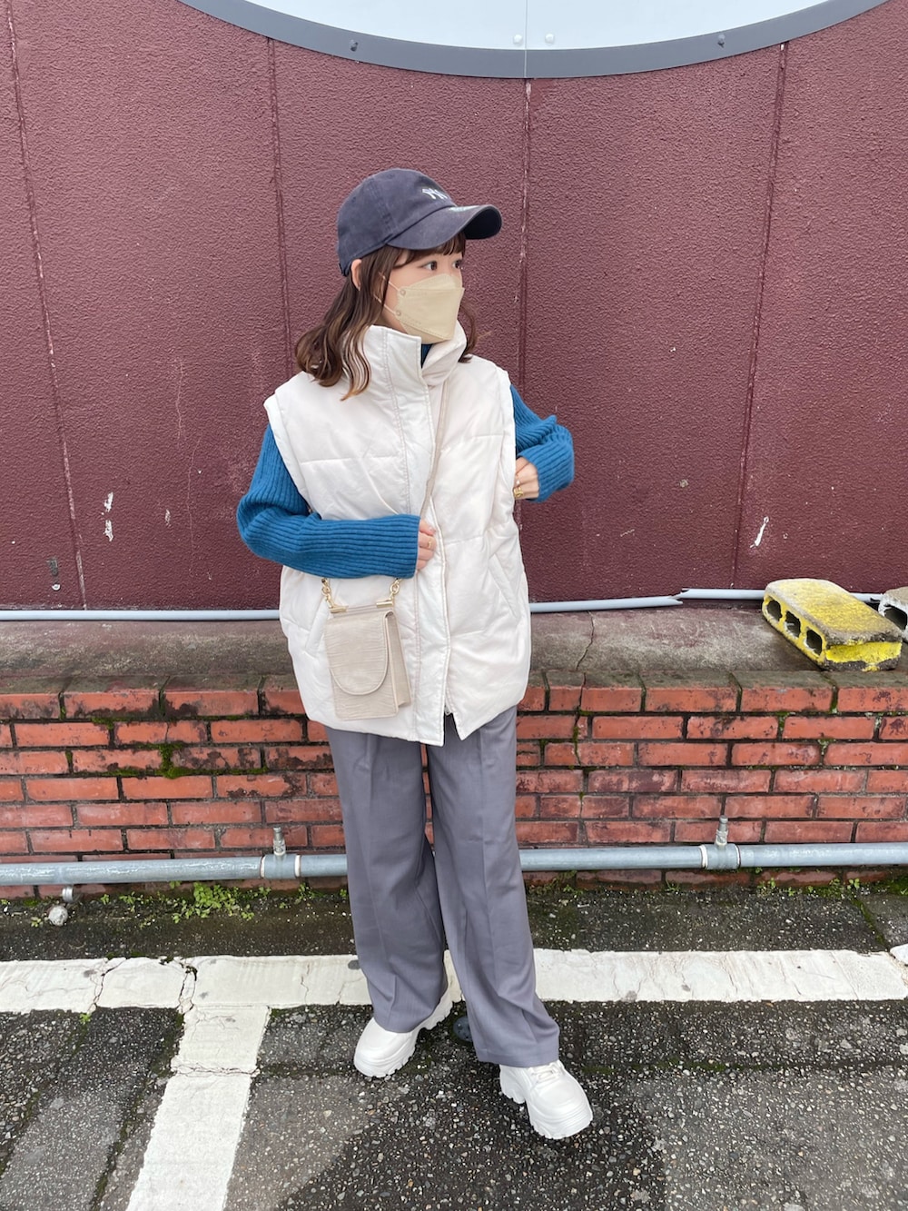 グレー系のパンツ、ブルー系のニット/セーター、ホワイト系のダウンベストを着用したレディースの冬コーディネートの5枚目の写真