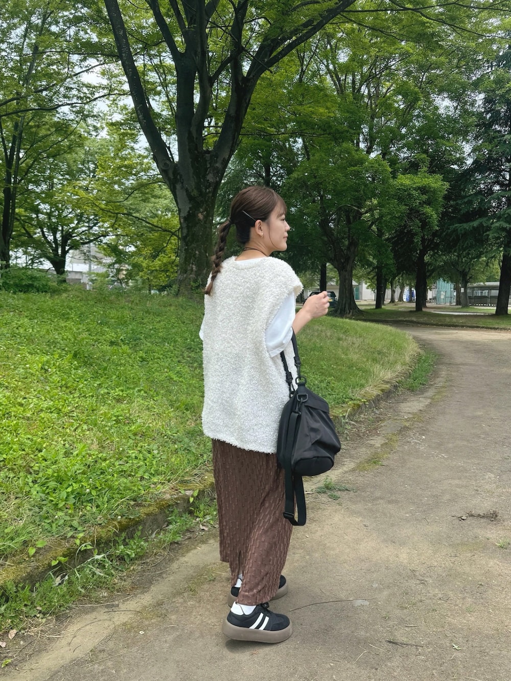 ブラウン系のスカート、ホワイト系のトップス、ブラック系のバッグを着用したレディースの夏コーディネートの4枚目の写真