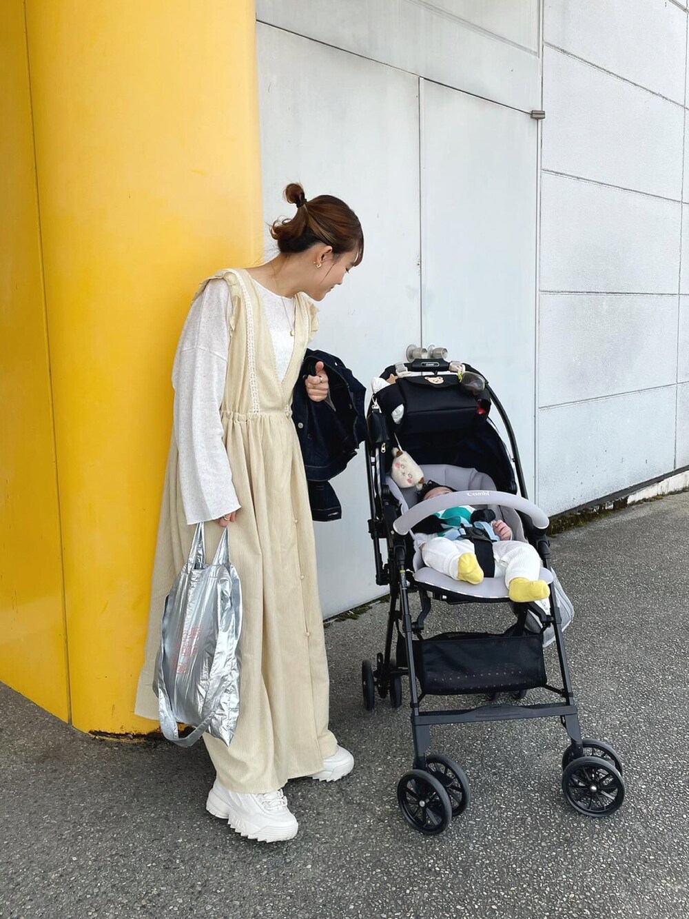 イエロー系のワンピース、ブルー系のデニムジャケット、シルバー系のトートバッグを着用したレディースの春コーディネートの2枚目の写真