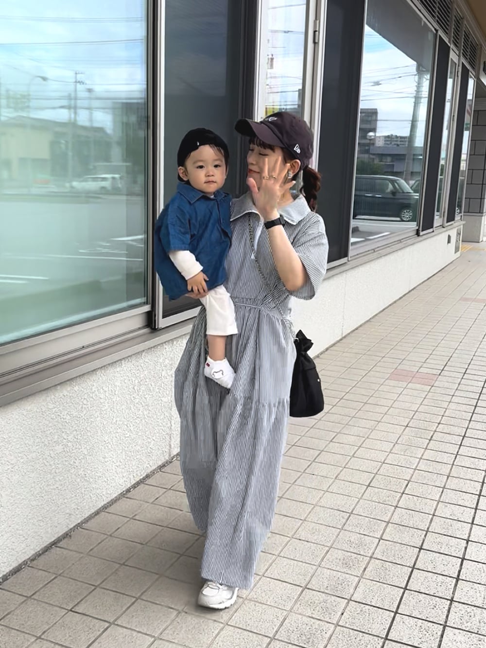 ブラック系のワンピース、ホワイト系のスニーカー、ブラック系のショルダーバッグを着用したレディースの夏コーディネートの2枚目の写真