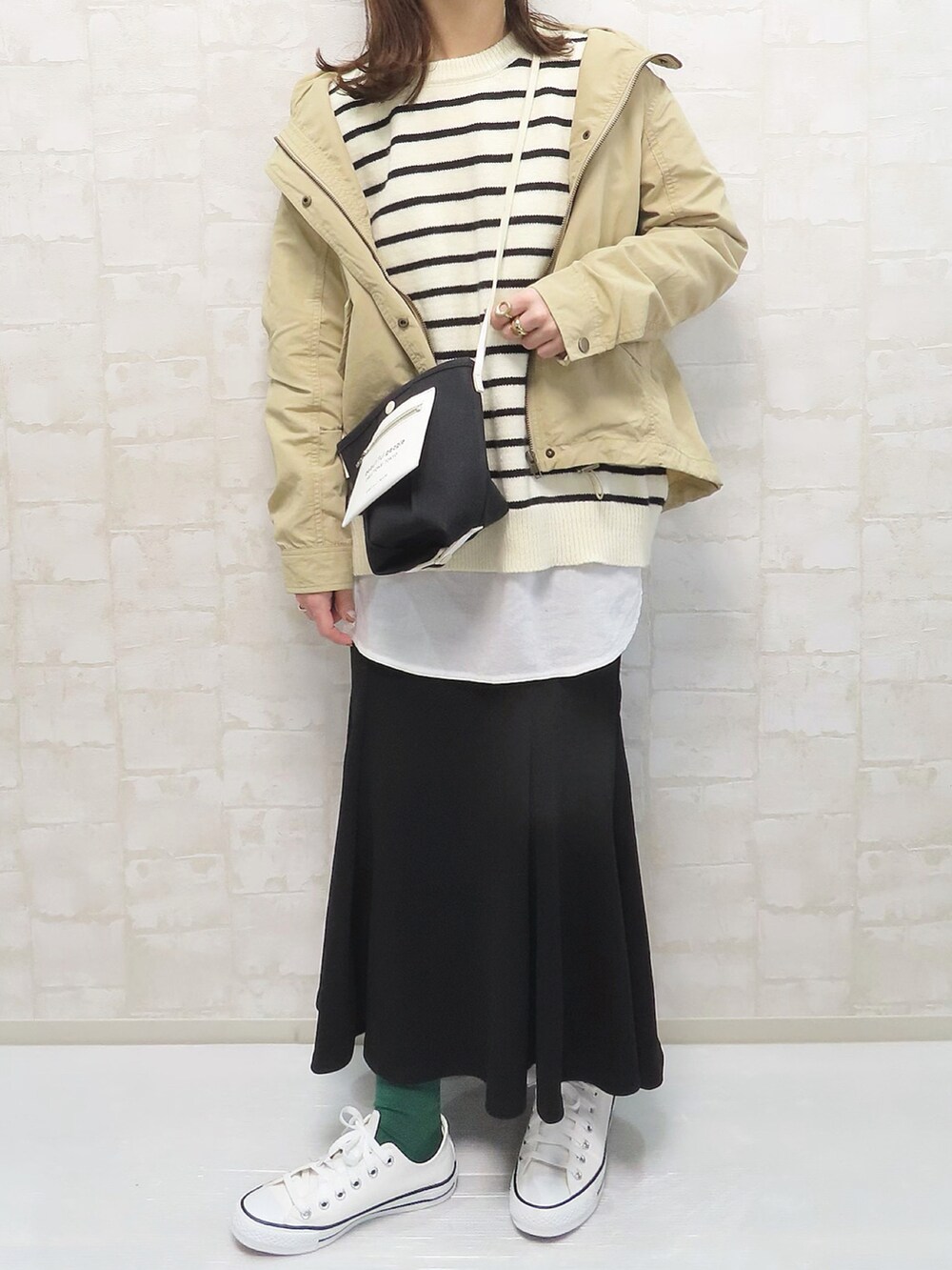 ベージュ系のマウンテンパーカー、ホワイト系のニット/セーター、ブラック系のスカートを着用したレディースの冬コーディネートの4枚目の写真