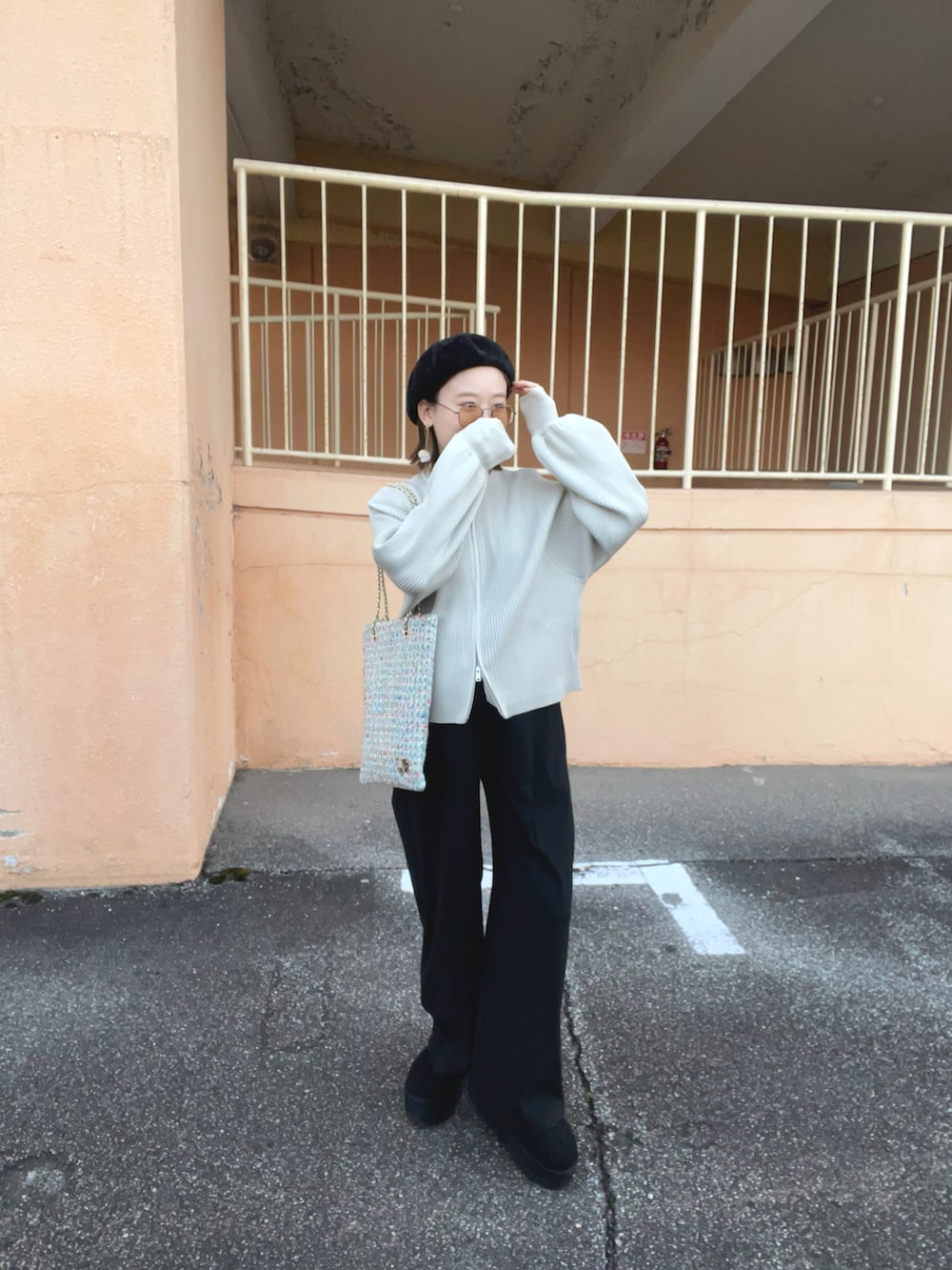 ホワイト系のカーディガン/ボレロ、グリーン系のトートバッグ、ブラック系のパンツを着用したレディースの秋コーディネートの4枚目の写真