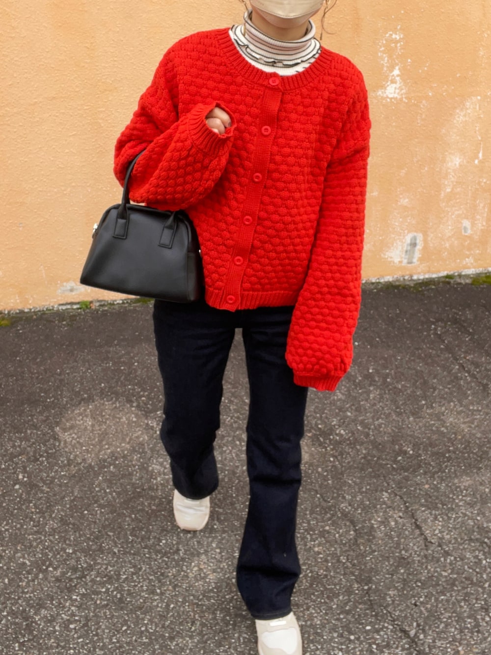 オレンジ系のカーディガン/ボレロ、ホワイト系のダウンベスト、ブラック系のスカートを着用したレディースの冬コーディネートの3枚目の写真