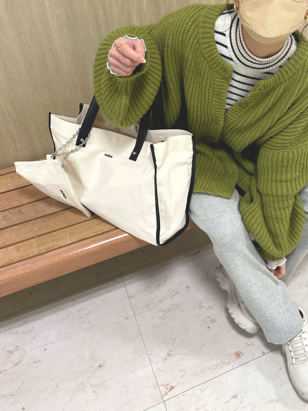 ホワイト系のトートバッグ、グリーン系のカーディガン/ボレロ、ホワイト系のニット/セーターを着用したレディースの冬コーディネートの3枚目の写真