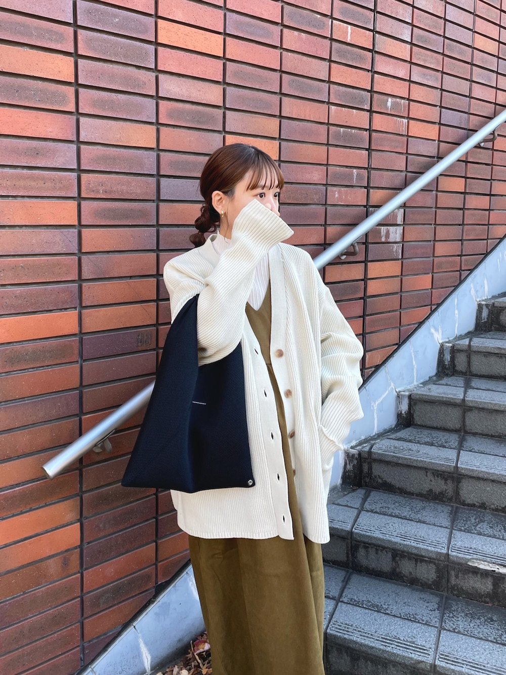 グリーン系のジャンパースカート、ホワイト系のニット/セーター、ホワイト系のカーディガン/ボレロを着用したレディースの冬コーディネートの5枚目の写真
