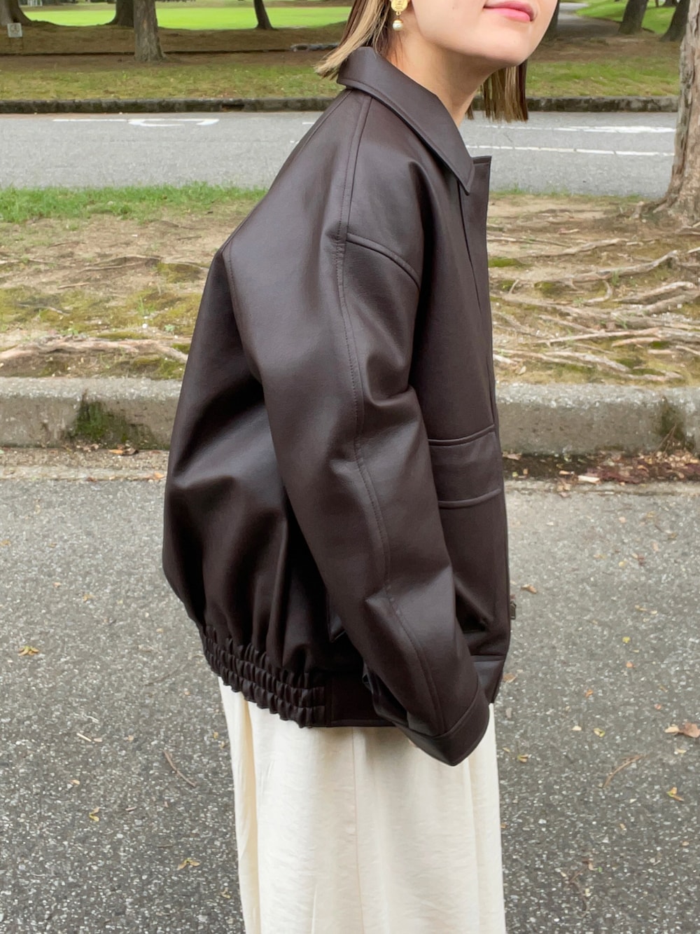 ブラック系のジャケット/アウター、ホワイト系のワンピース、ブラック系のブーツを着用したレディースの秋コーディネートの2枚目の写真