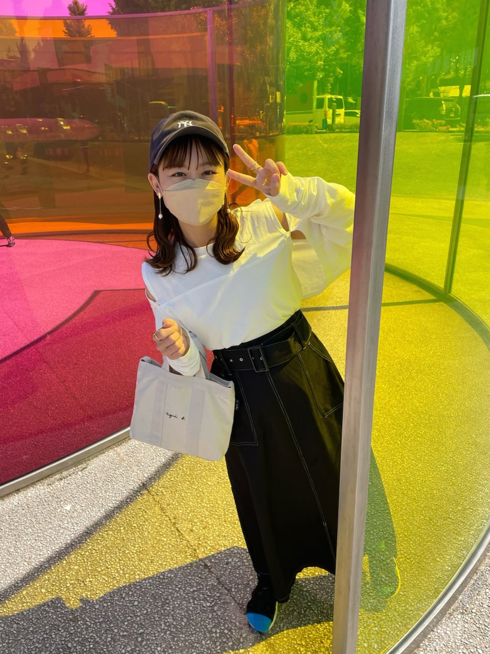 ホワイト系のトートバッグ、ホワイト系のトップス、ブラック系のスカートを着用したレディースの春コーディネートの5枚目の写真