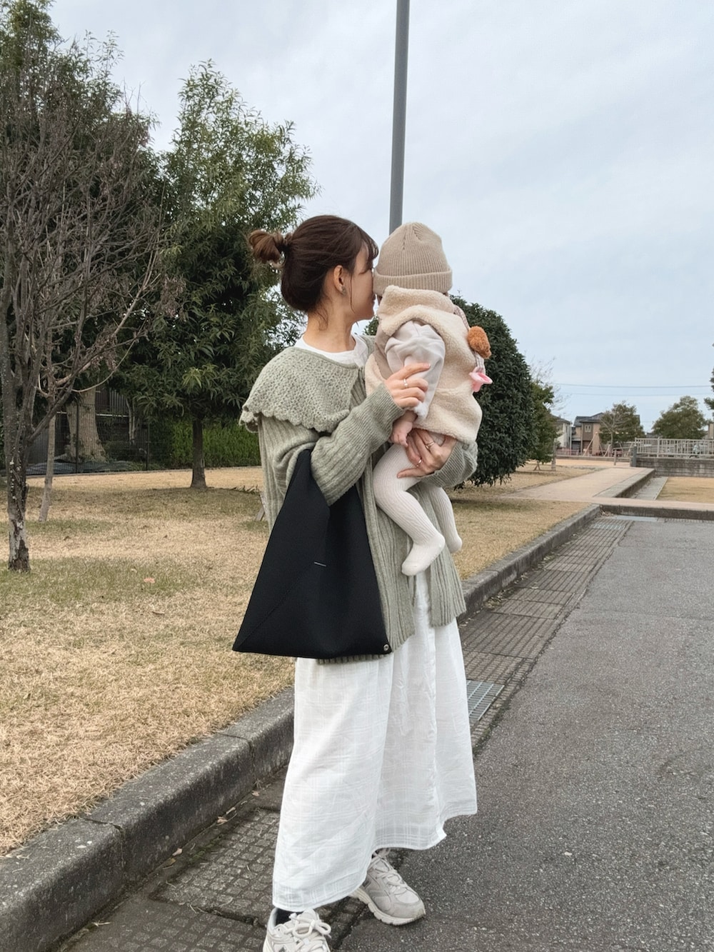 ブラック系のトートバッグ、ホワイト系のスニーカー、グリーン系のカーディガン/ボレロを着用したレディースの冬コーディネートの4枚目の写真