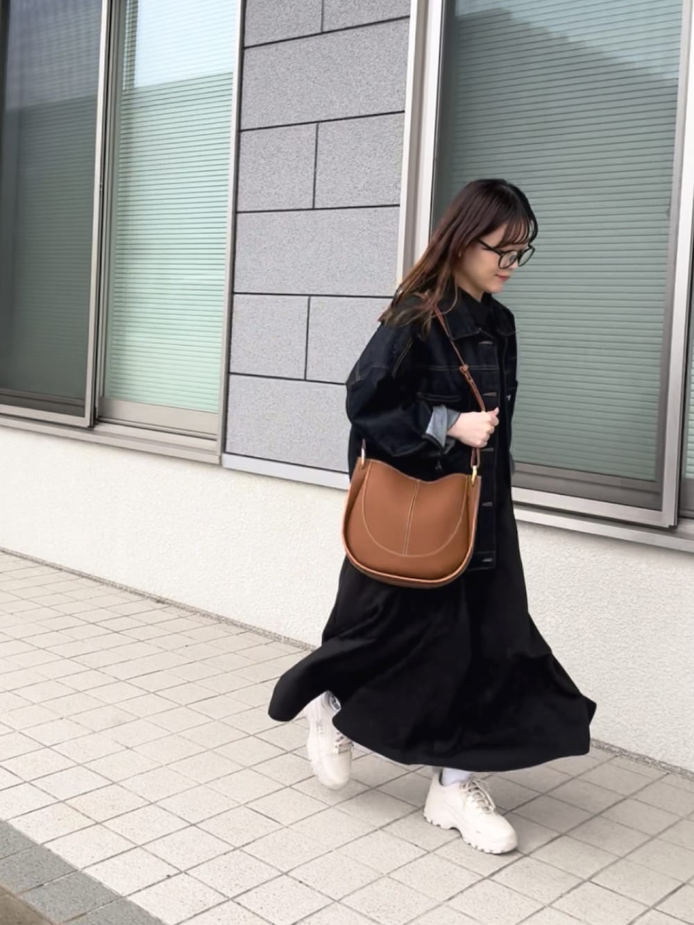 ブラック系のワンピース、ブラウン系のショルダーバッグ、ブルー系のデニムジャケットを着用したレディースの春コーディネートの3枚目の写真