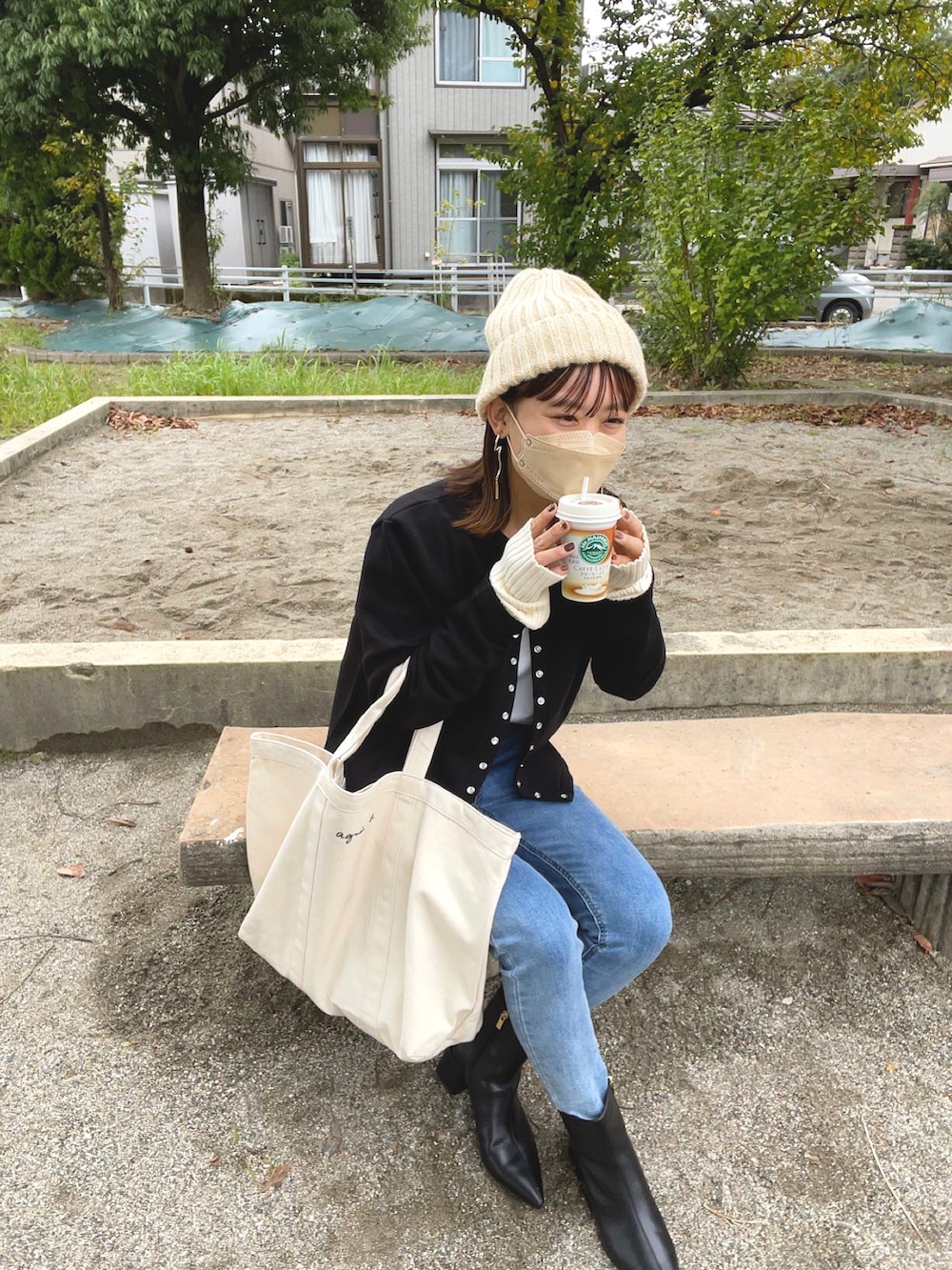 ホワイト系のトートバッグ、ブラック系のブーツ、ブルー系のデニムパンツを着用したレディースの秋コーディネートの5枚目の写真