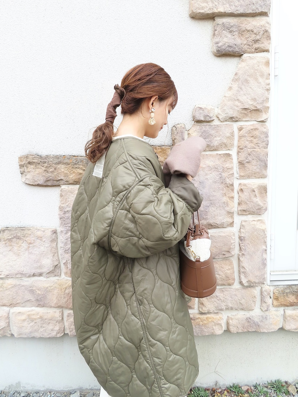 グリーン系のノーカラーコート、ベージュ系のワンピース、ホワイト系のTシャツ/カットソーを着用したレディースの秋コーディネートの4枚目の写真