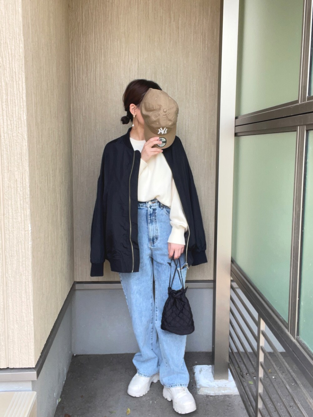 ブラック系のブルゾン、ホワイト系のニット/セーター、その他のデニムパンツを着用したレディースの春コーディネートの3枚目の写真