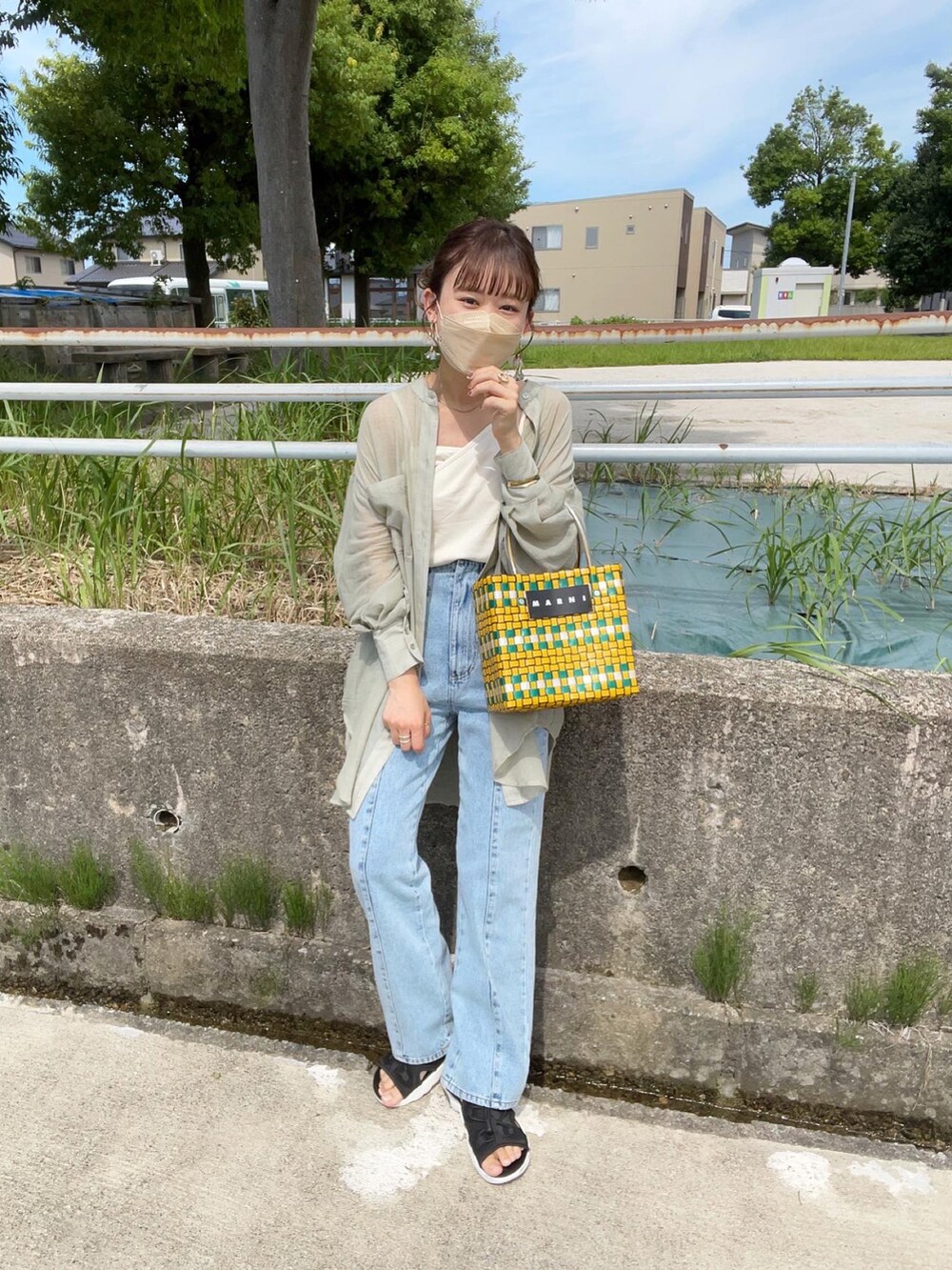 グリーン系のシャツ/ブラウス、ホワイト系のキャミソール、ブルー系のデニムパンツを着用したレディースの夏コーディネートの3枚目の写真