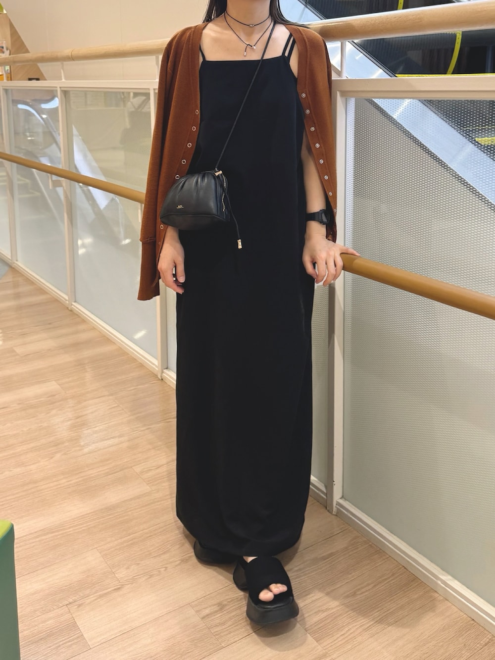 イエロー系のカーディガン/ボレロ、ブラック系のワンピース、ブラック系のショルダーバッグを着用したレディースの夏コーディネートの2枚目の写真