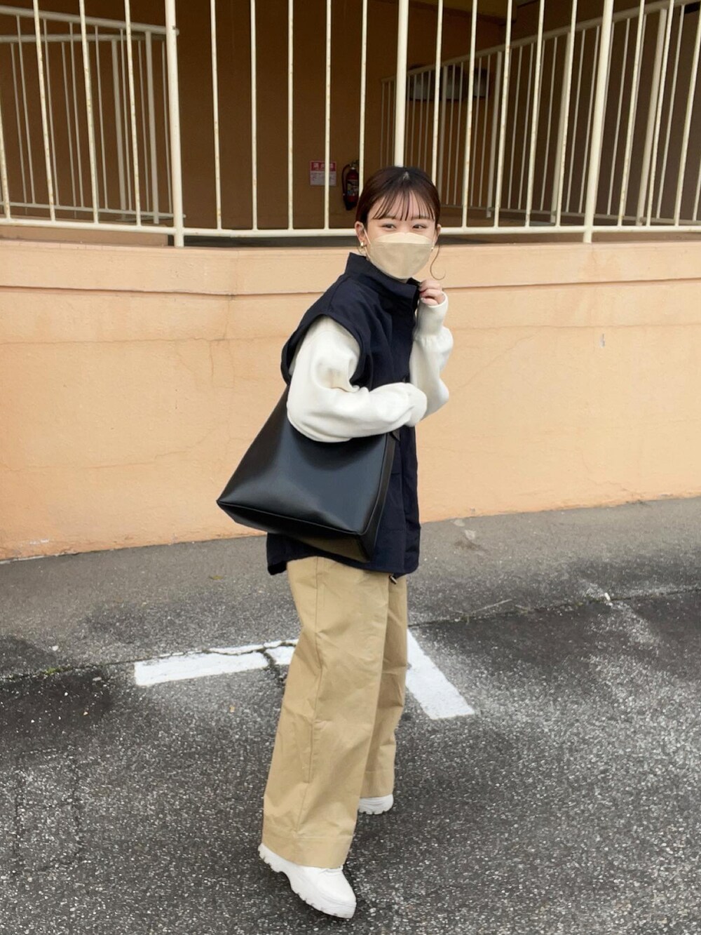 ベージュ系のその他パンツ、ホワイト系のニット/セーター、ブラック系のマウンテンパーカーを着用したレディースの春コーディネートの4枚目の写真