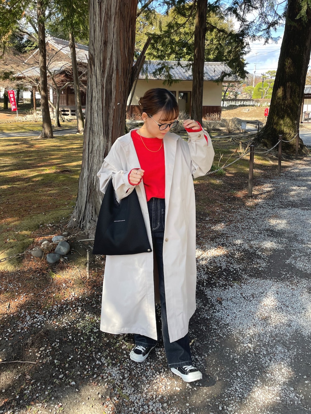 ベージュ系のトレンチコート、レッド系のニット/セーター、ブラック系のデニムパンツを着用したレディースの春コーディネートの5枚目の写真