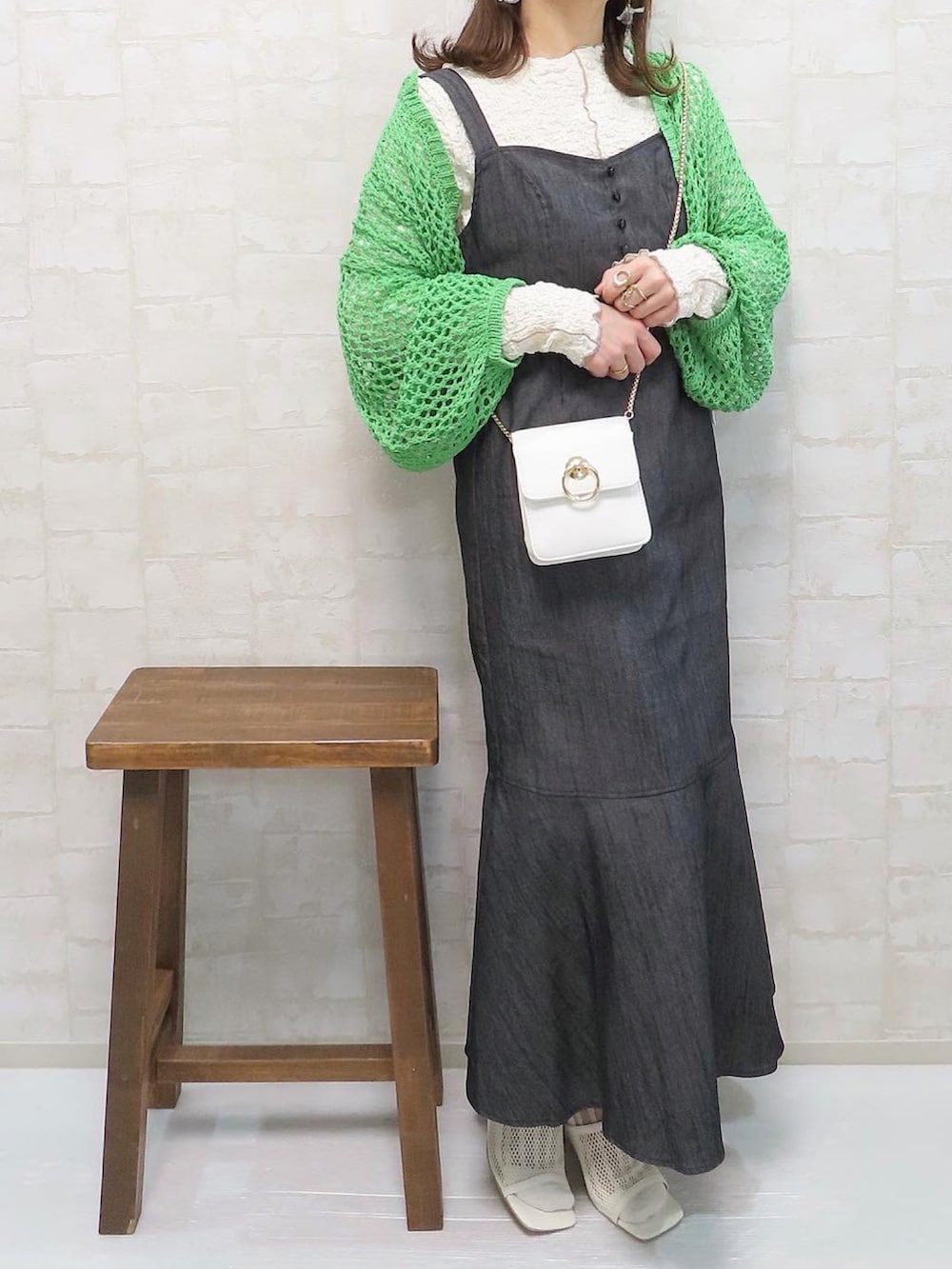 ブラック系のジャンパースカート、グリーン系のカーディガン/ボレロ、ホワイト系のTシャツ/カットソーを着用したレディースの春コーディネートの3枚目の写真