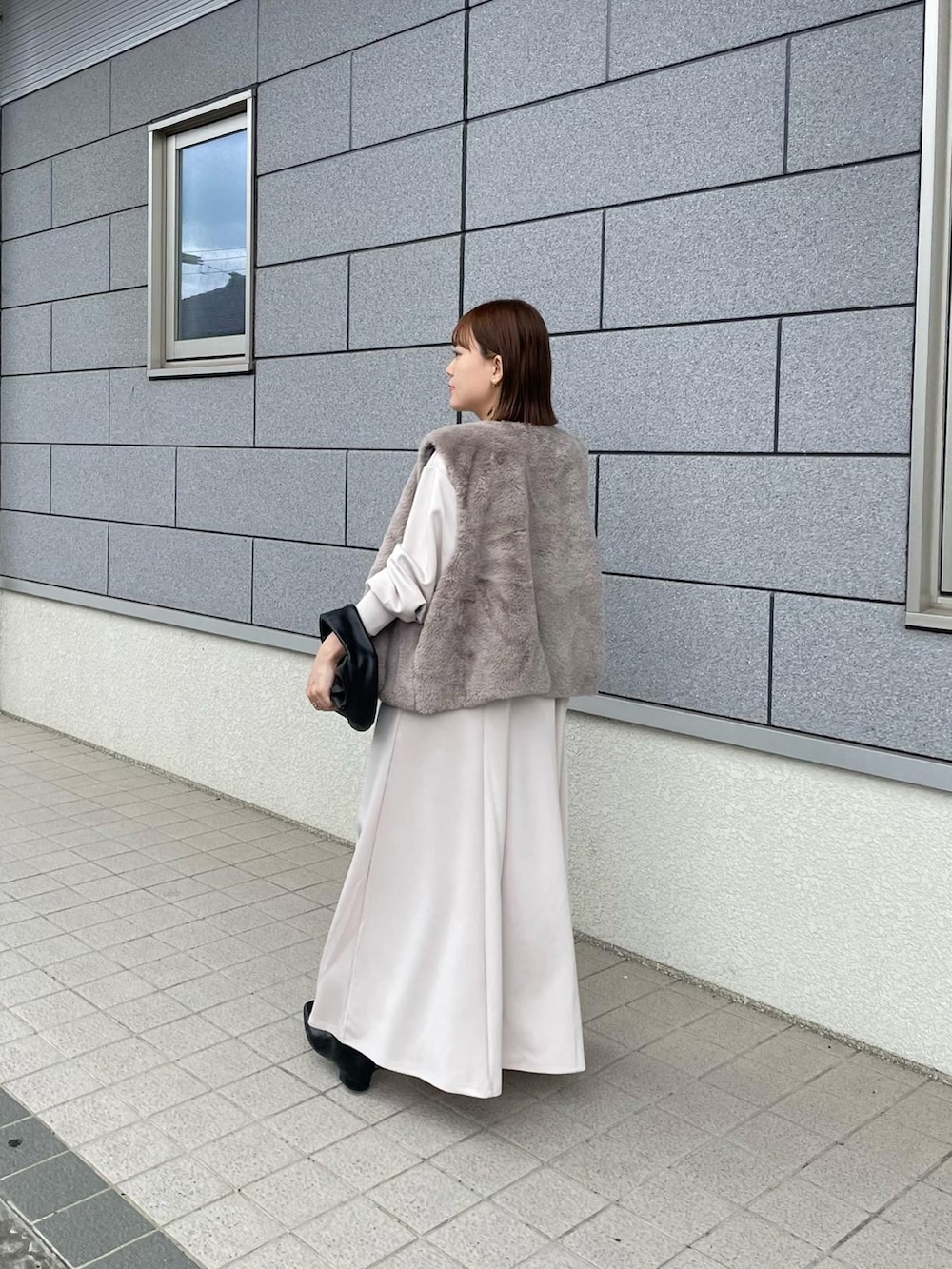 ホワイト系のワンピース、ベージュ系のその他アウター、ブラック系のハンドバッグを着用したレディースの秋コーディネートの2枚目の写真