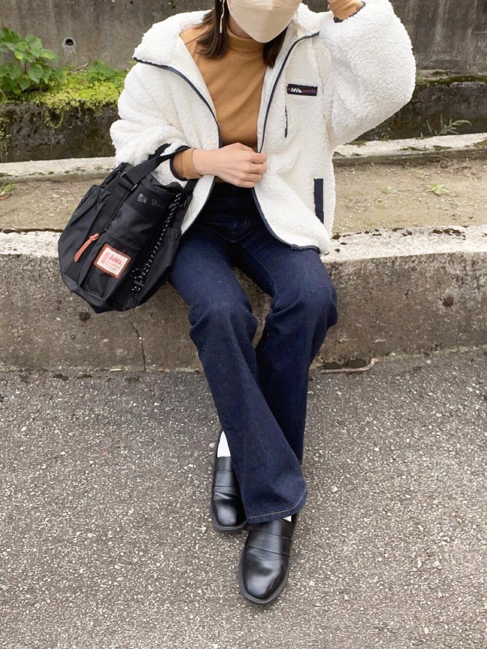 ホワイト系のブルゾン、イエロー系のトップス、ブルー系のデニムパンツを着用したレディースの冬コーディネートの3枚目の写真