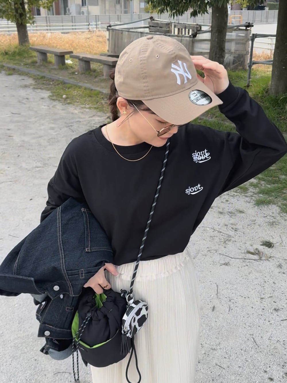 ブラック系のTシャツ/カットソー、ホワイト系のスカート、ブラック系のバッグを着用したレディースの春コーディネートの2枚目の写真